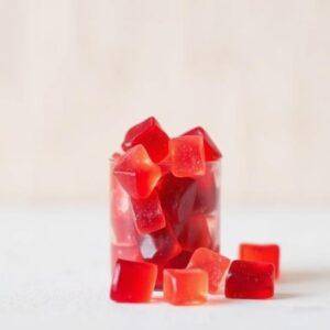 Red square gummies in a glass, representing weight loss gummies