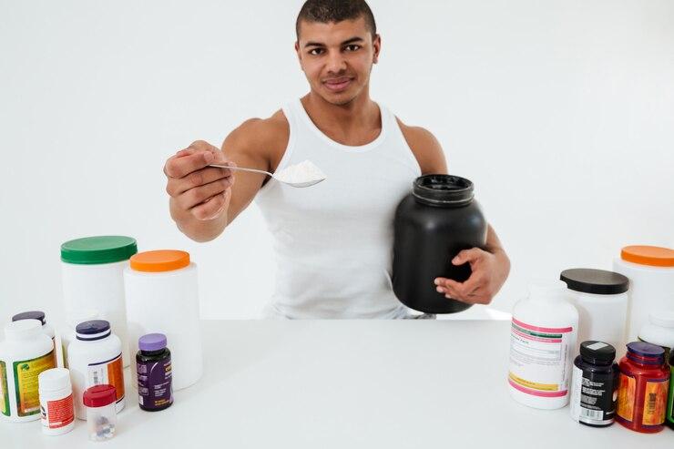 sportsman-standing-white-wall-holding-vitamins