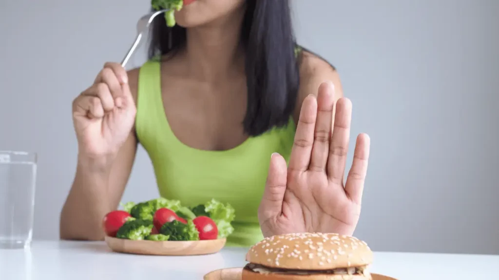 Balancing health and temptation: A burger is refused as broccoli is eaten, showcasing a mindful approach to diet.