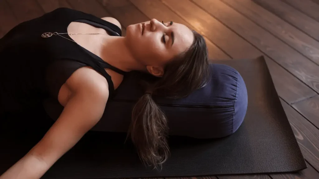 Finding stillness: A woman resting comfortably on a yoga bolster, showcasing a moment of profound relaxation.